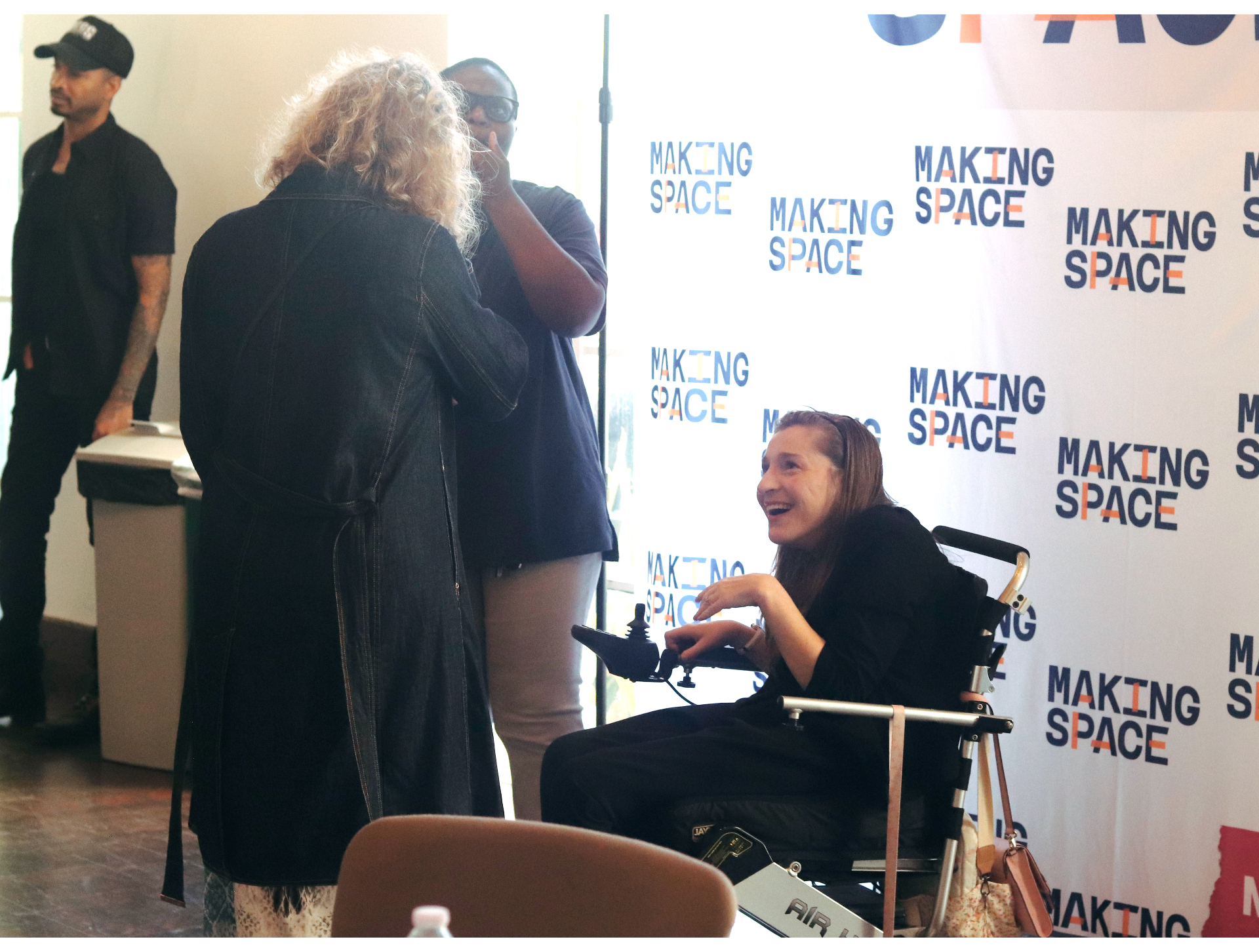 A member laughing with others in front of a Making Space step-and-repeat backdrop